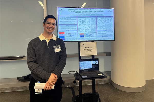 A researcher smiling while presenting a digital poster titled "Coadministration of Detemir-Tesaglitazar with Semaglutide Increases Therapeutic Benefit" at the ACCM Research Day.